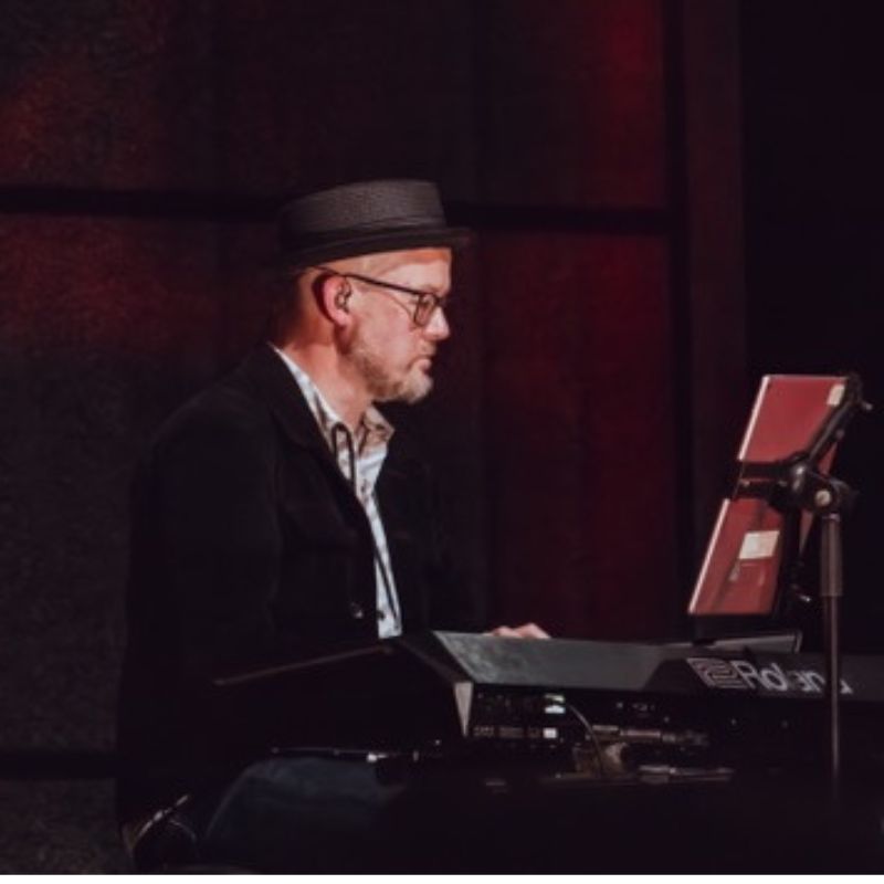 Jon Trier wearing Cosmic ears custom IEMs and playing the keyboard