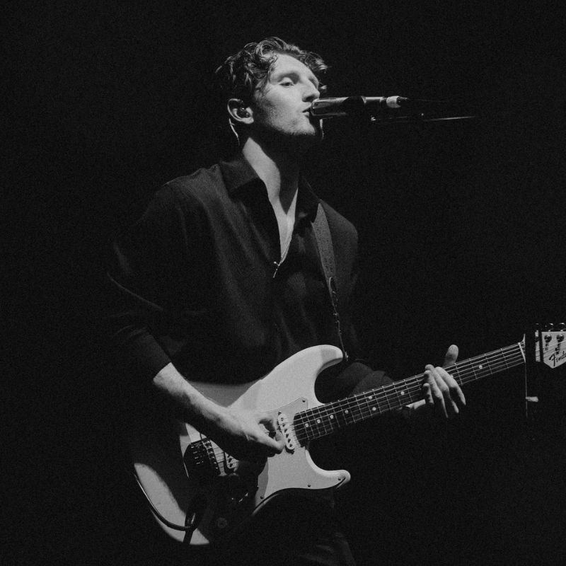 Pearce Mcmenamin from The Clause playing guitar on stage wearing Cosmic Ears custom in-ear monitors